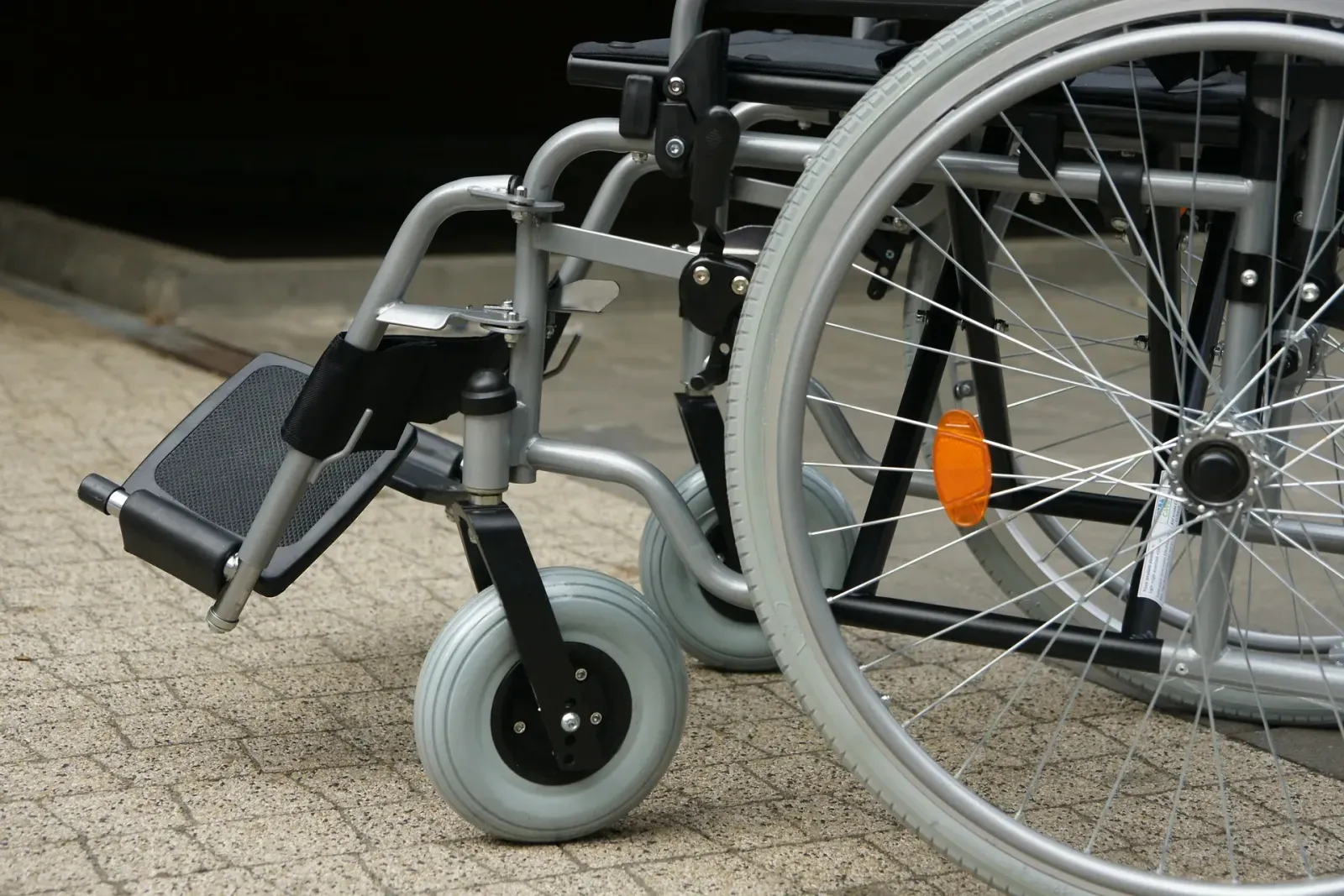 Manual wheelchair wheels and footrest on a brick sidewalk in Palm Beach County, FL